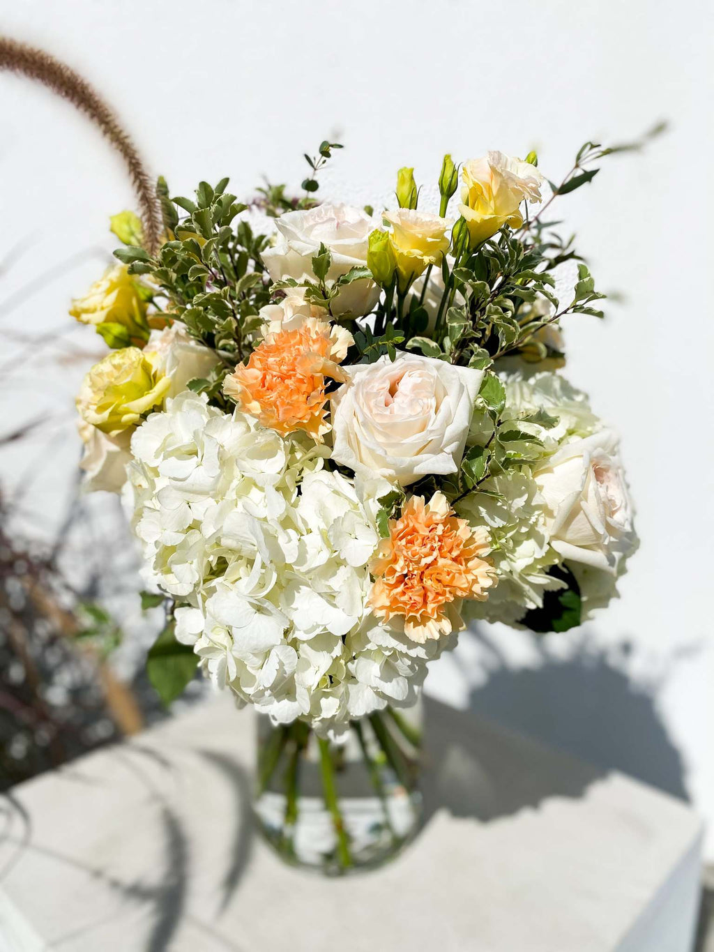 Gabriella bouquet by Margot Floral Design. A fresh flower bouquet composed of Pink Roses, White Hydrangeas, Orange and Yellow Carnations. Medium size.