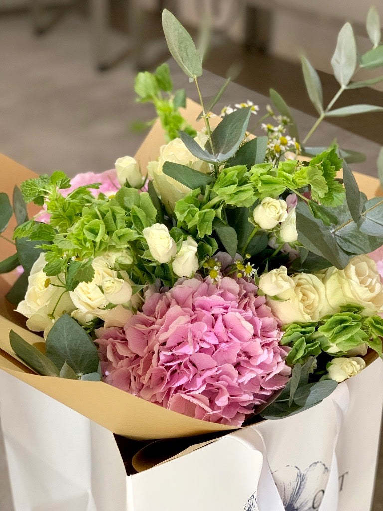 Hermione bouquet by Margot Floral Design. A fresh flower bouquet composed of White O'Hara Garden Roses, Pink Hydrangeas, and Eucalyptus. Medium size.
