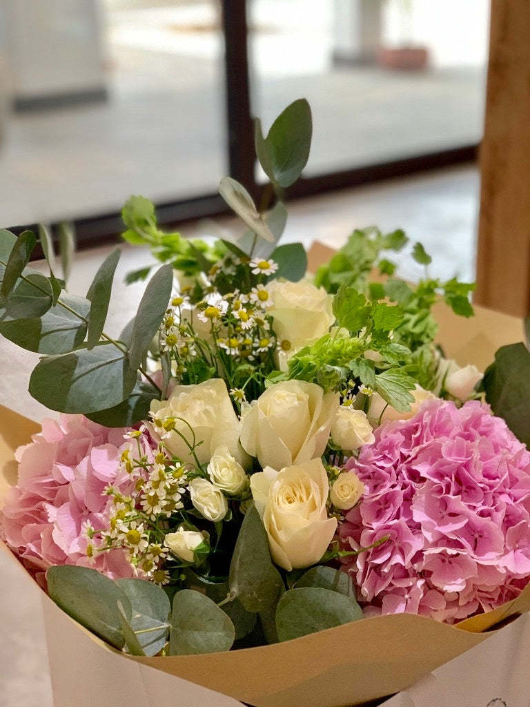 Hermione bouquet by Margot Floral Design. A fresh flower bouquet composed of White O'Hara Garden Roses, Pink Hydrangeas, and Eucalyptus. Medium size.
