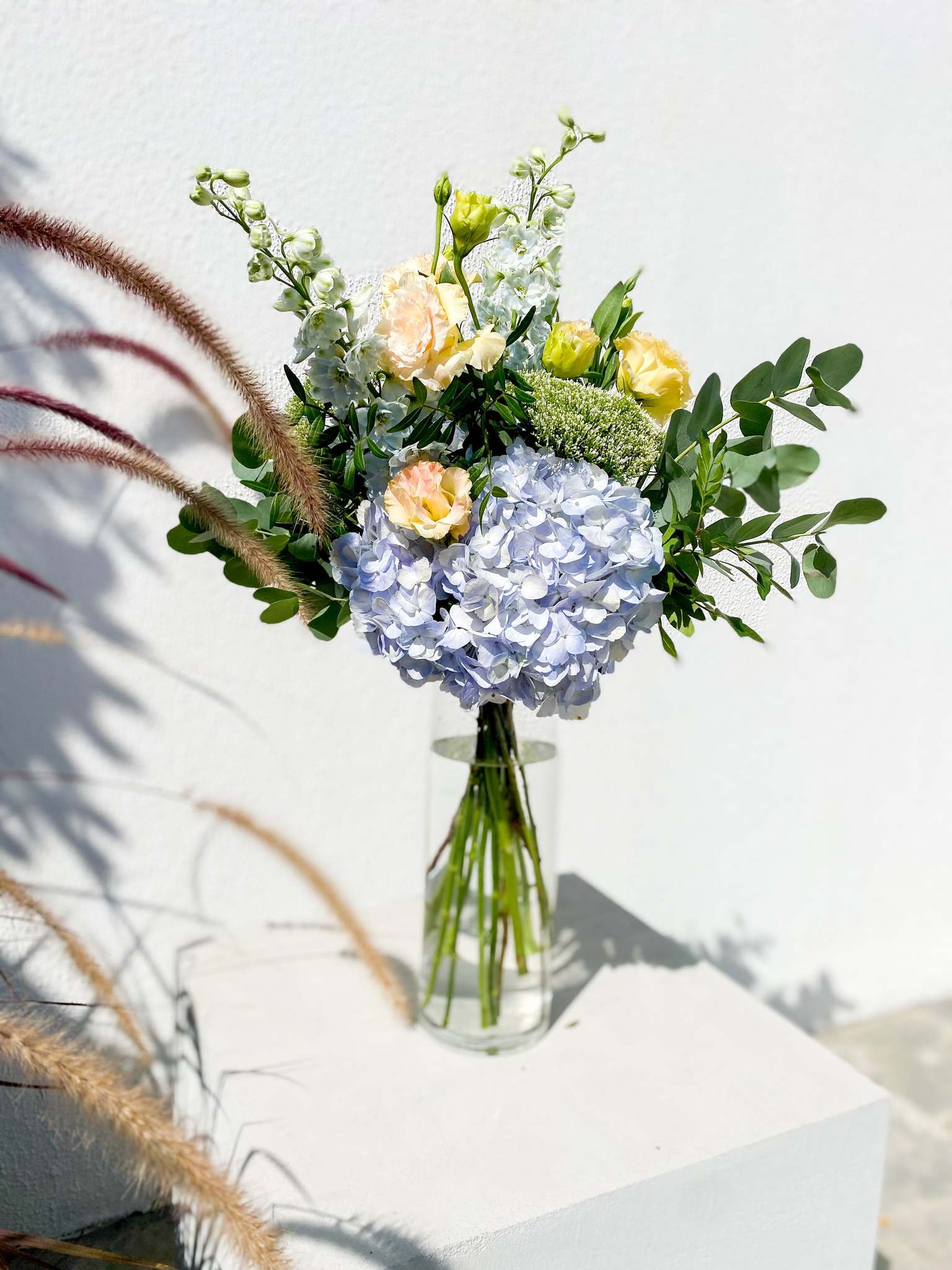 Valentine bouquet by Margot Floral Design. A fresh flower bouquet composed of Pale Yellow Roses, White Delphinium, Blue Hydrangea, and Eucalyptus. Small Size.