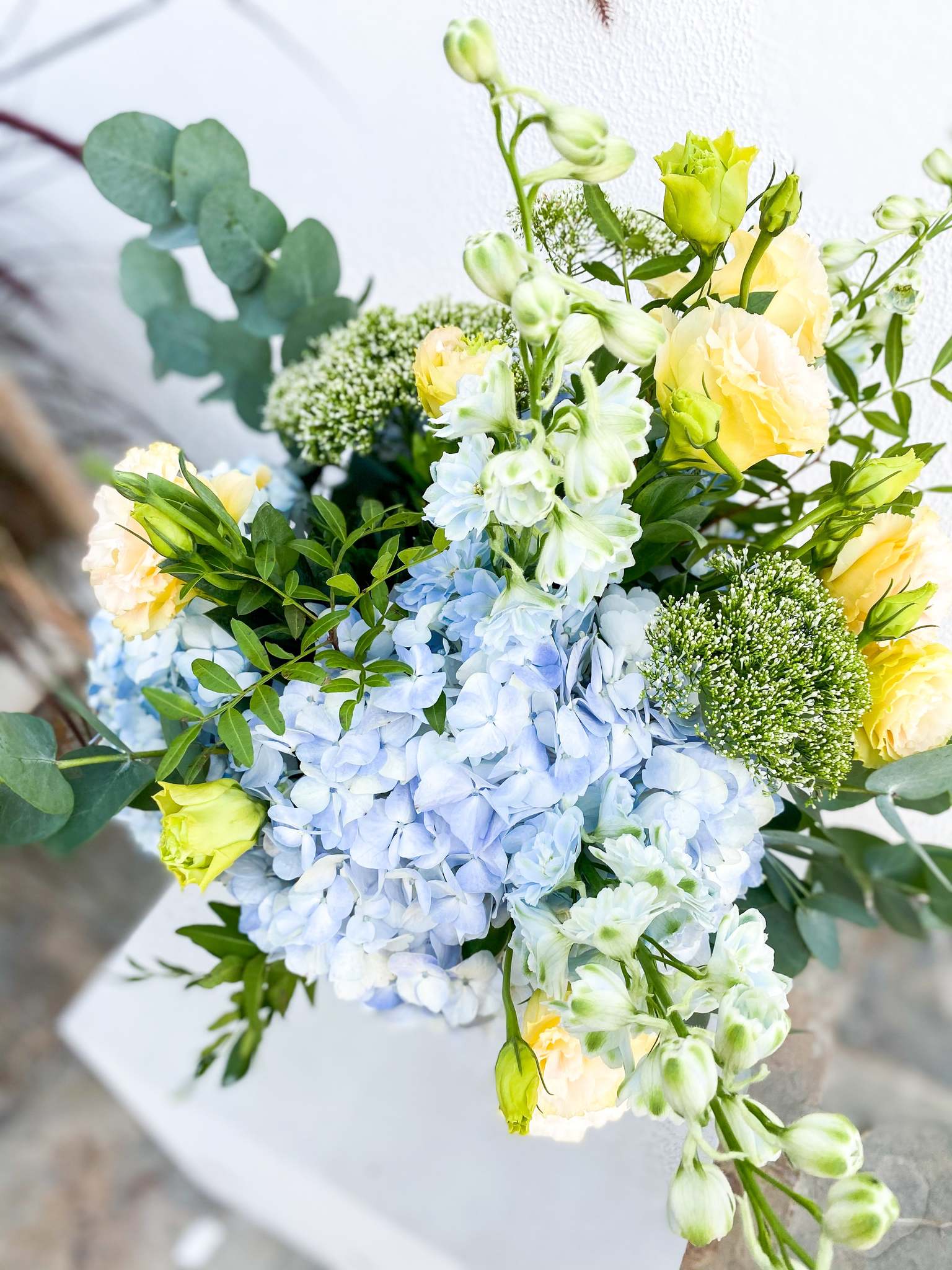 Valentine bouquet by Margot Floral Design. A fresh flower bouquet composed of Pale Yellow Roses, White Delphinium, Blue Hydrangea, and Eucalyptus. Large Size.